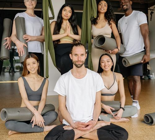 Diverse group of people smiling in a bright yoga studio.